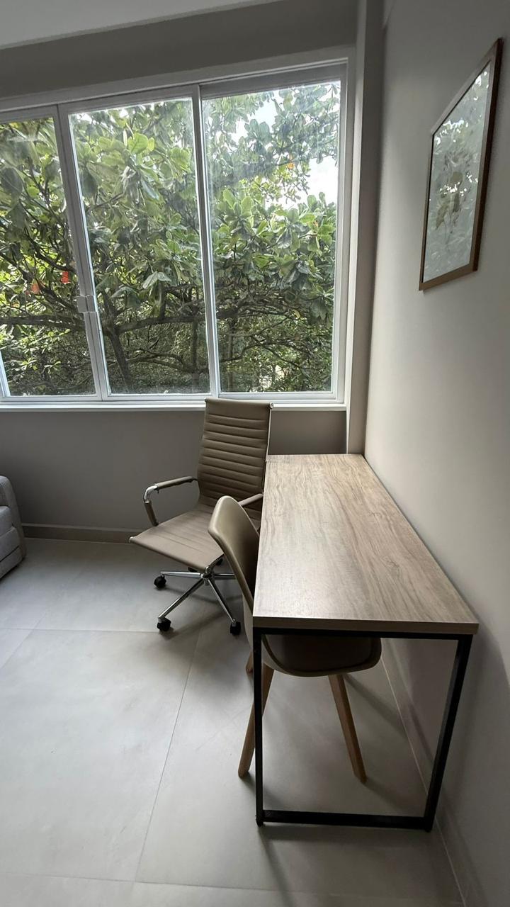 Sala de atendimento com mesa de madeira e vista para árvores